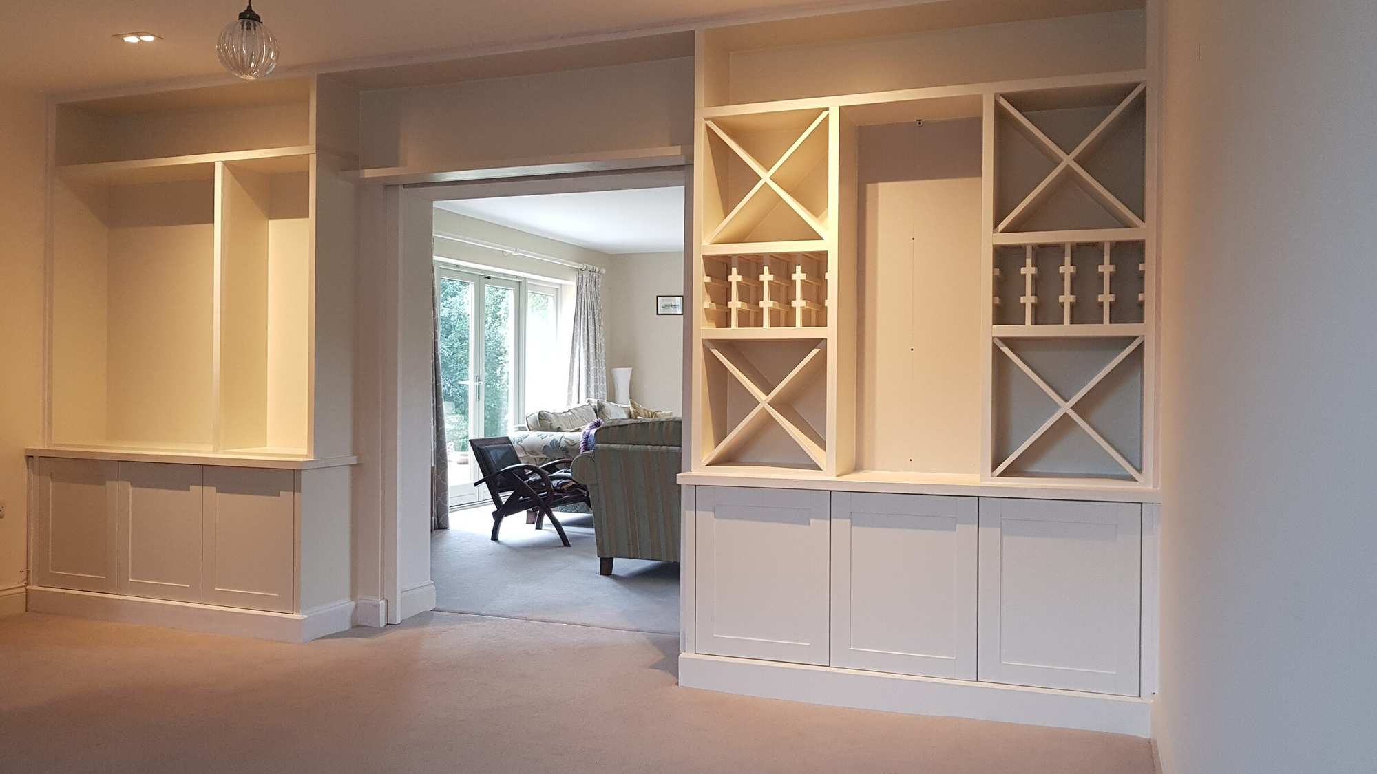 Fitted alcove units with wine racks either side of a wide opening