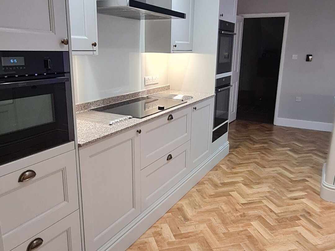 An induction hob and built-in oven in a run of cream units