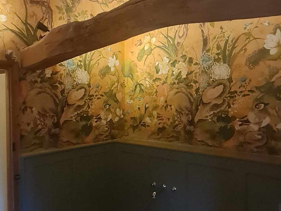 Floral wallpaper above the panelling, under the beam