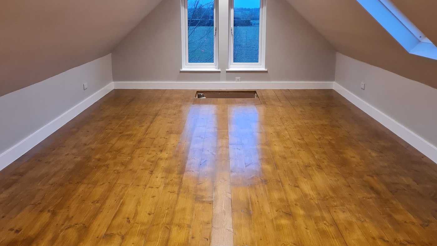 The room above the cart lodge: a sanded wooden floor and windows at the gable end
