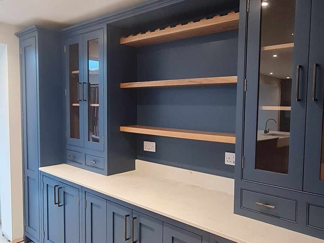 A navy dresser with glazed cabinets and open oak shelves
