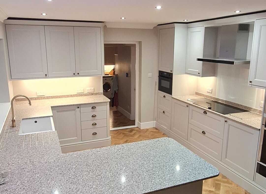 A cream shaker kitchen with granite worktops and a herringbone wood block floor