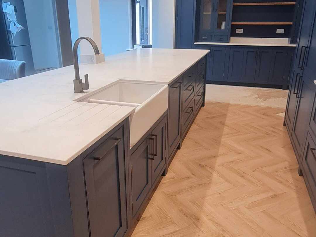 A Belfast sink set into the white worktop of the navy island